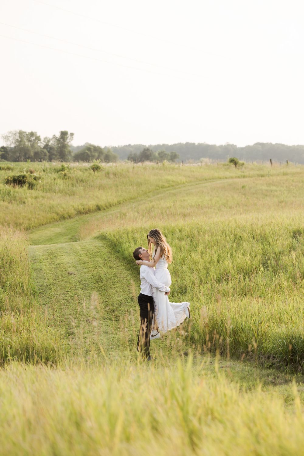 A romantic moment captured along a grassy path with soft natural lighting.