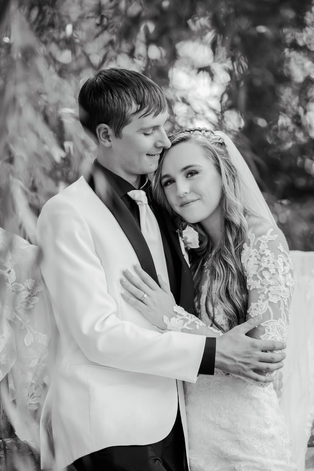 Black and white intimate portrait under willow trees with soft lighting.