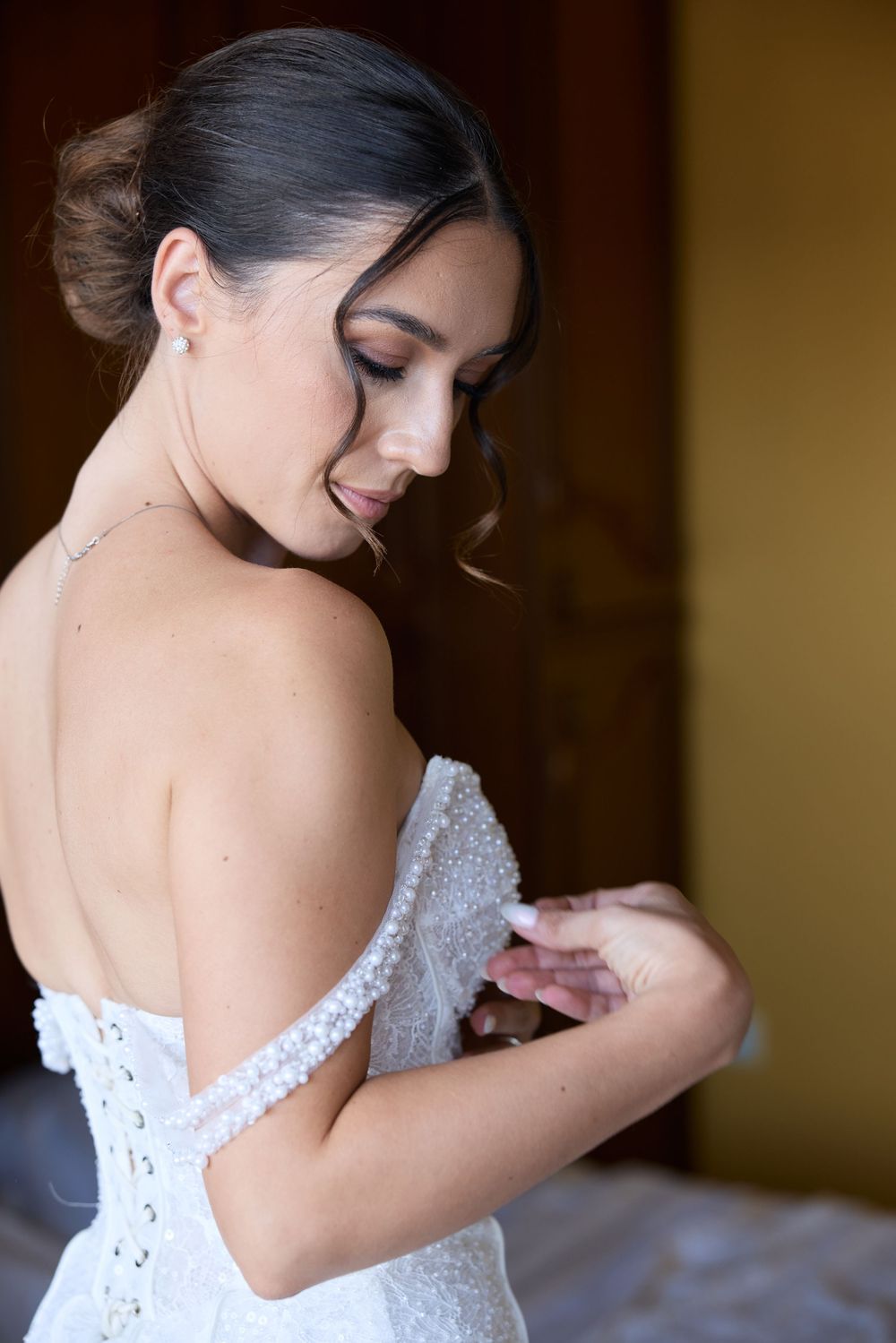 Close-up details of a white beaded wedding dress being fastened.