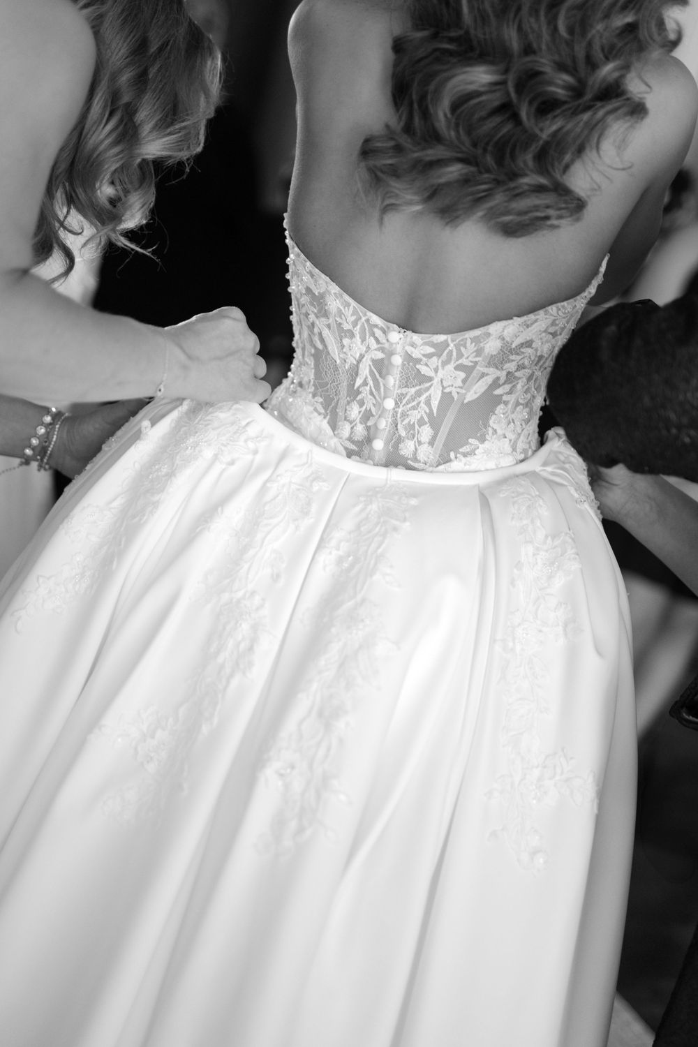Close-up details of a white wedding dress with delicate lace bodice and flowing fabric.
