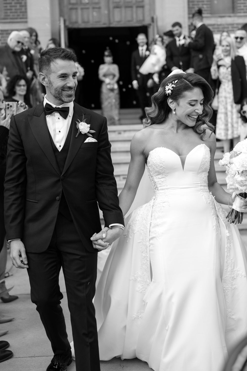 Wedding party in formal attire walking and laughing together at an outdoor venue.