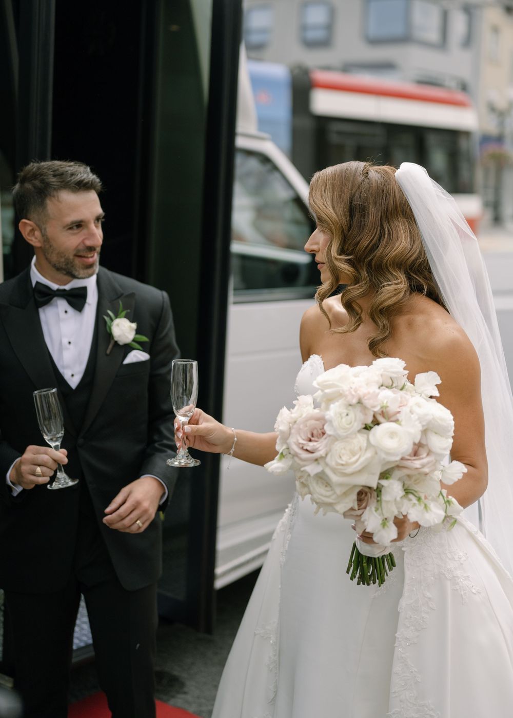 Elegant wedding scene with white rose bouquets and formal attire during outdoor celebration.