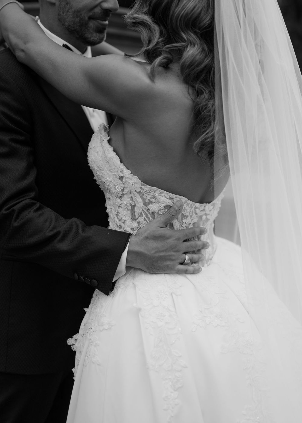Black and white photo of a couple embracing during their first dance at a wedding reception.