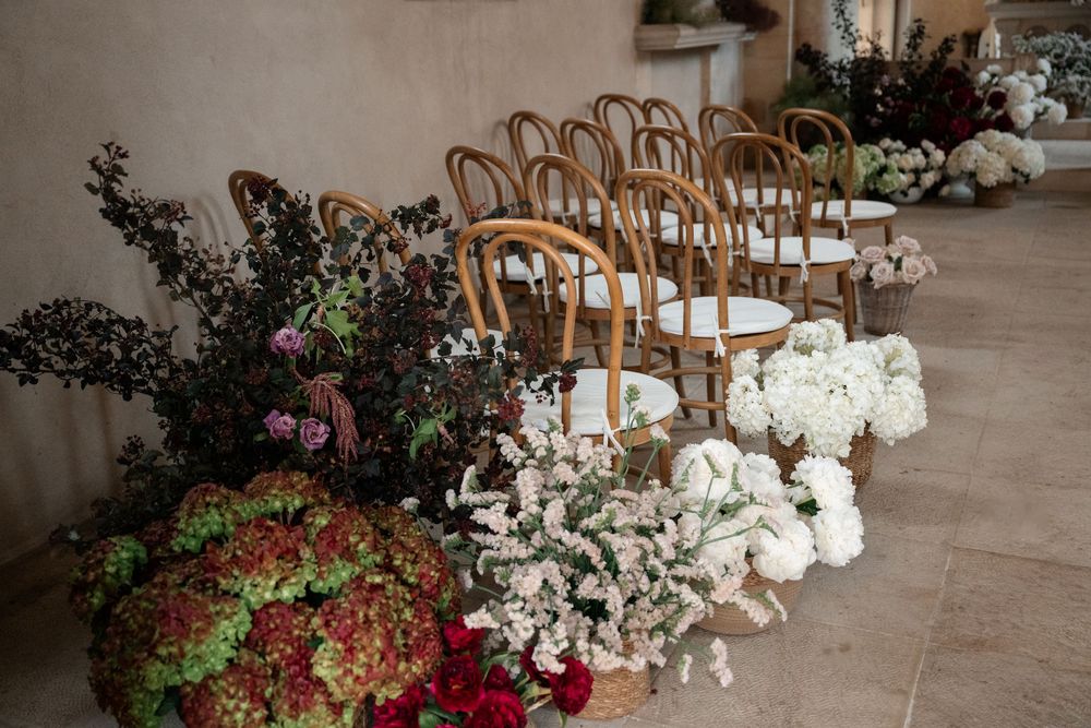 Elegant floral arrangements with white orchids and roses line a wedding reception venue's walkway.