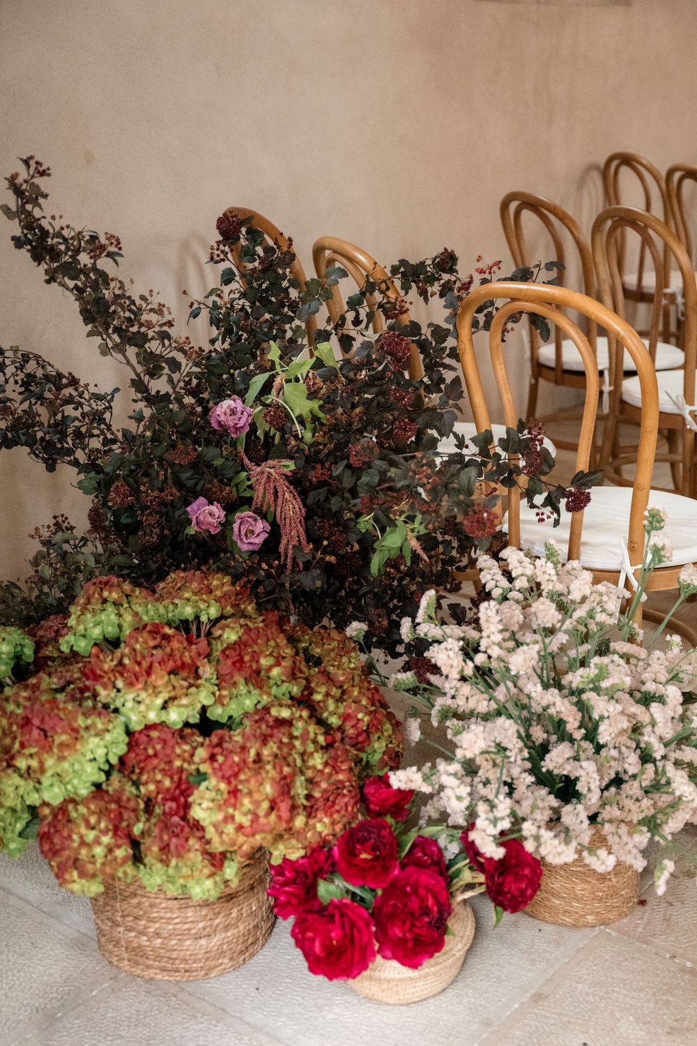Beautiful floral arrangements in woven baskets featuring red roses, white flowers, and greenery against a light backdrop.