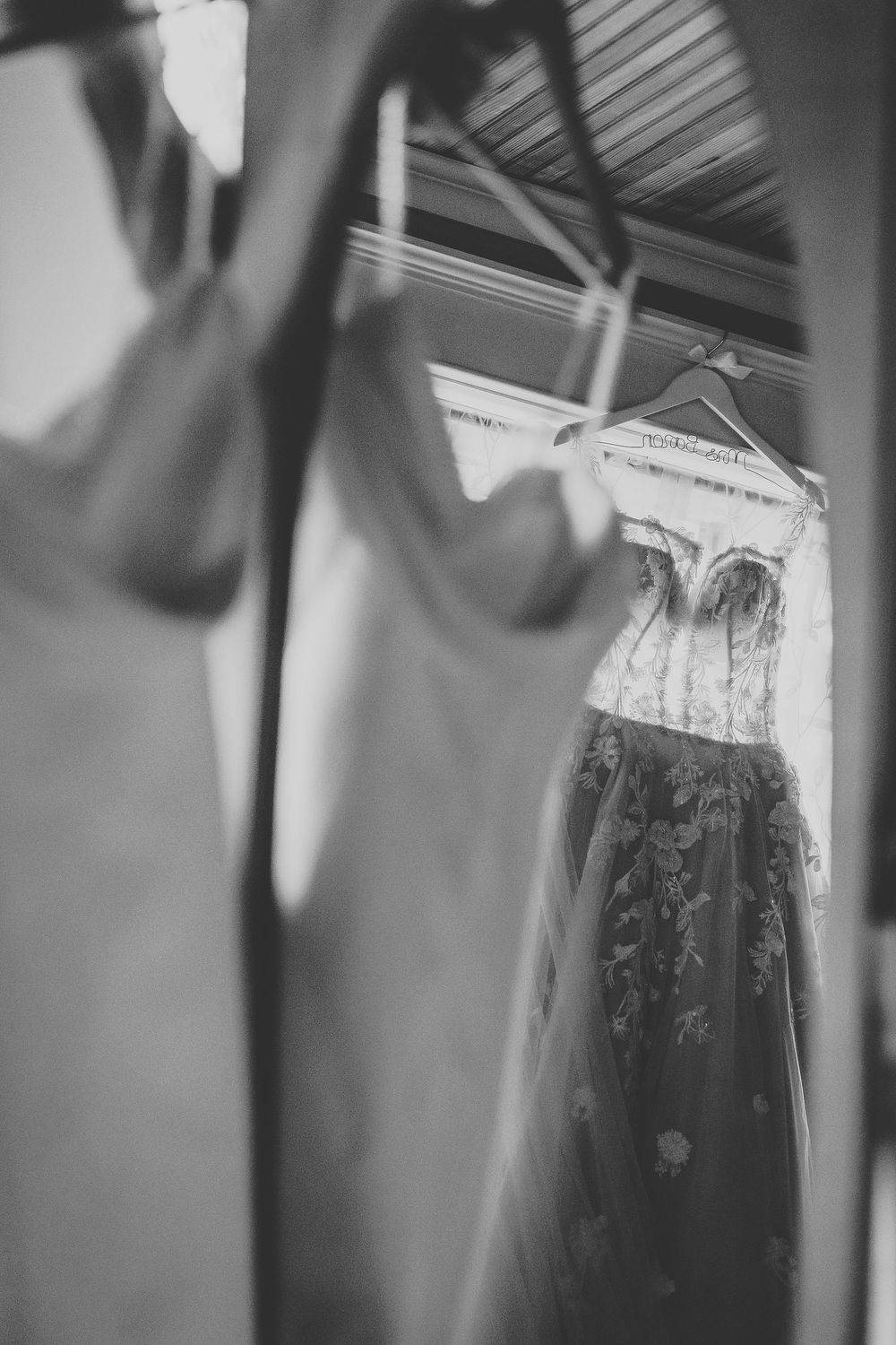 The wedding and reception dress hanging in the bridal suite reflecting off a mirror