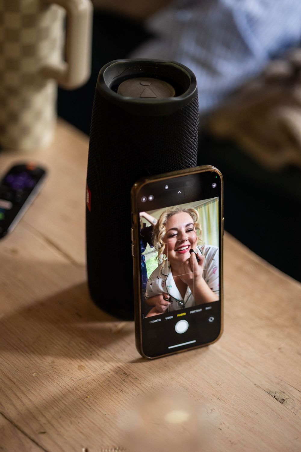 The bride using the camera on her phone to apply her lipstick before she puts her dress on