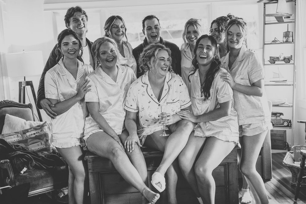 The brides and her wedding party posing on a bench in their pajamas before the ceremony at the airbnb