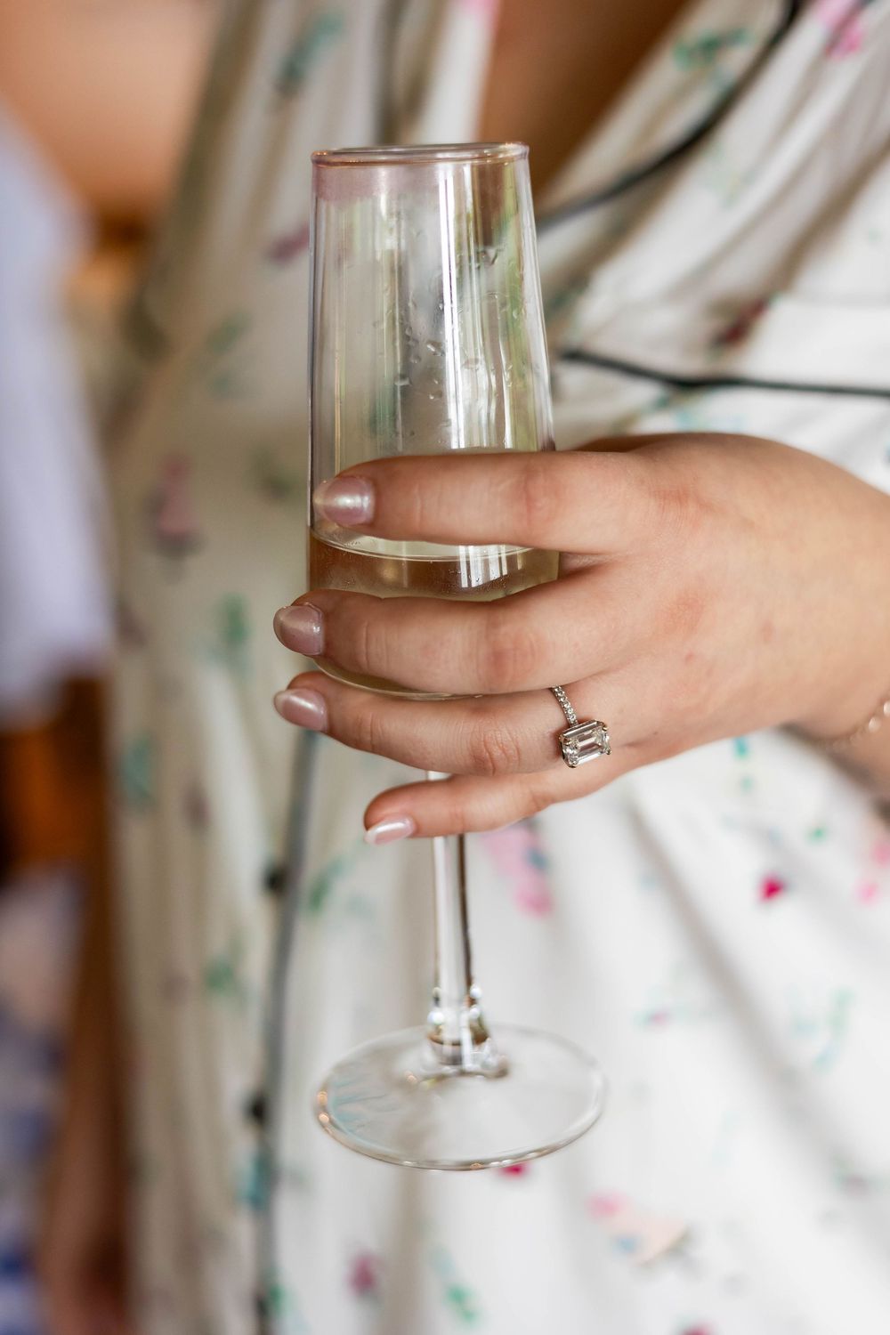 The bride holding her glass of champagne with her wedding engagement ring shining in the sunlight