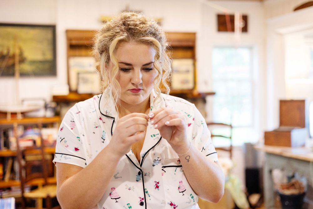 A bride in her getting ready robe untangling her necklace in the kitchen