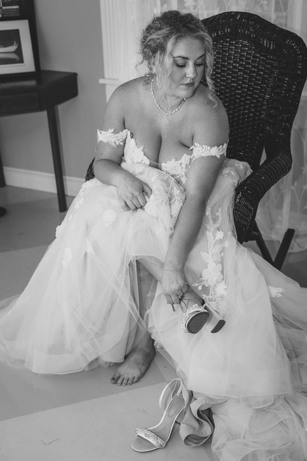 Black and white photo series showing a bride names Marina in a white wedding dress putting on elegant bridal shoes.
