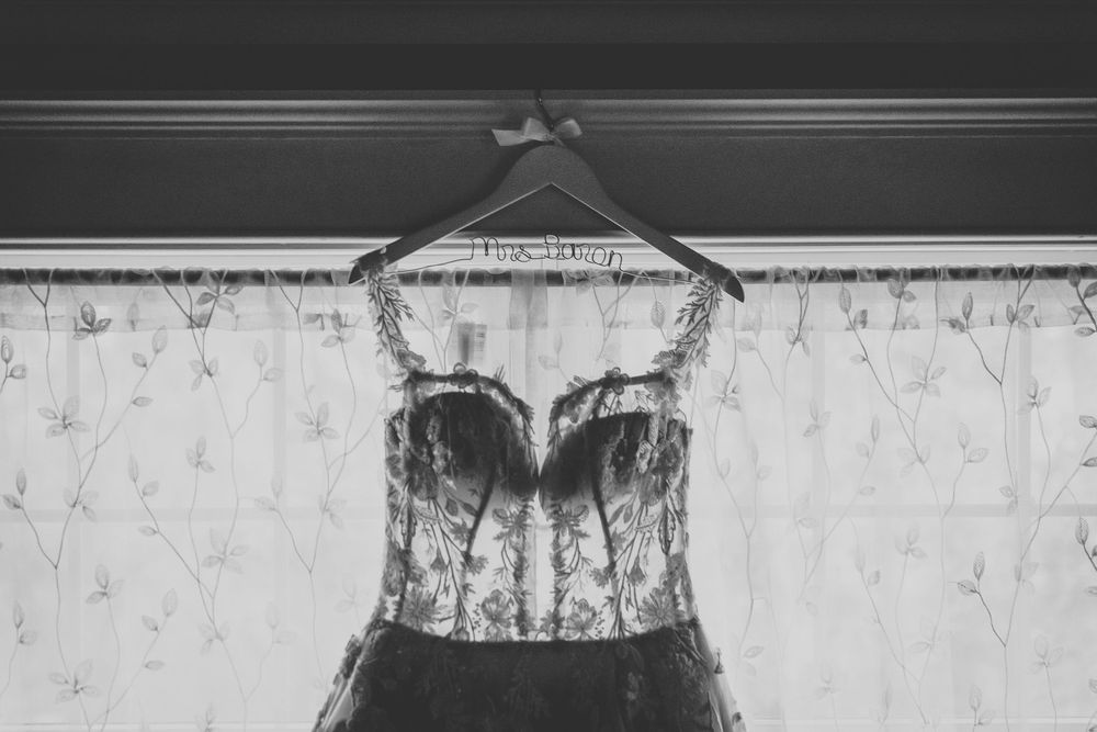 A close-up view of a wooden door frame with showing texture and age with the top of a lace sheer wedding dress