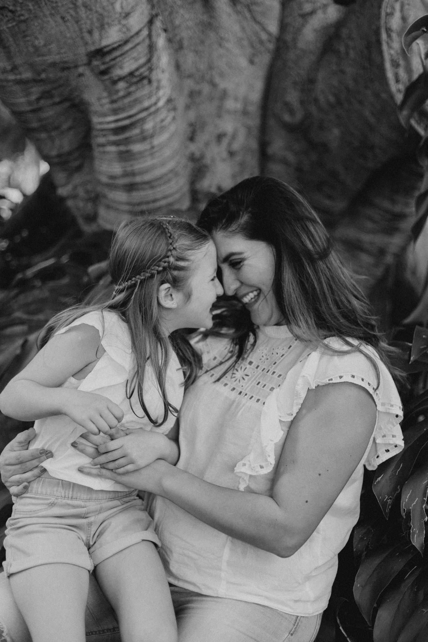 Black and white portrait of tender moment shared between child and adult outdoors.