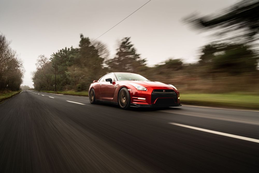 Red sports car drifting on a racetrack with motion blur and dramatic lighting effects.