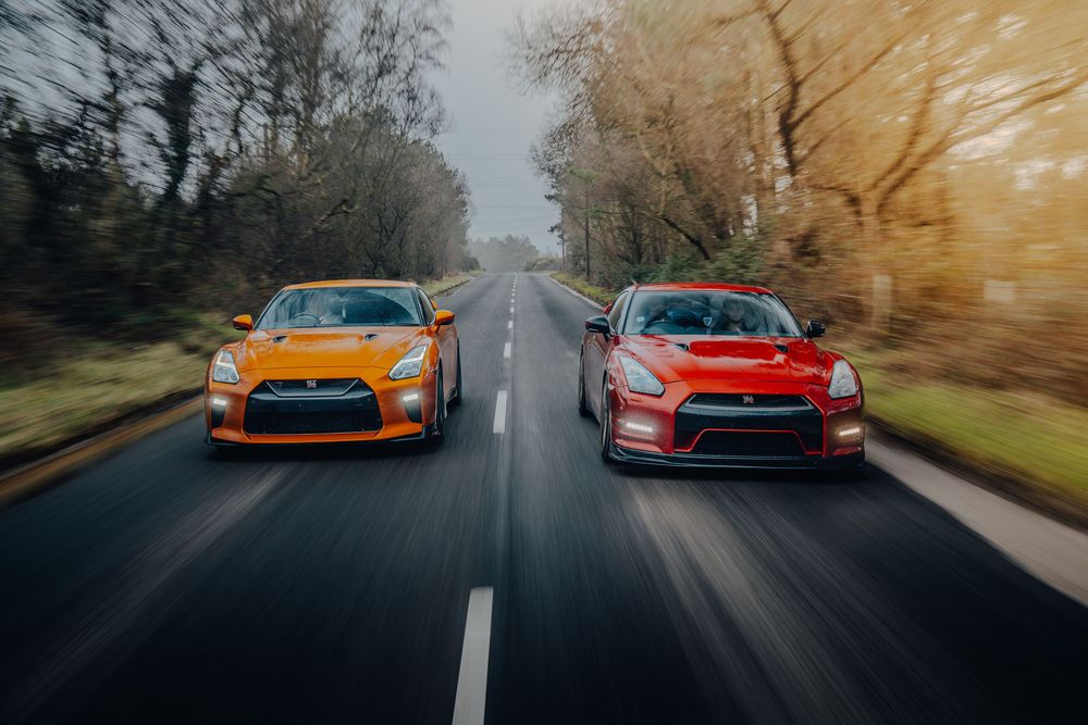 Orange and red sports cars racing down a misty forest road during golden hour sunset.