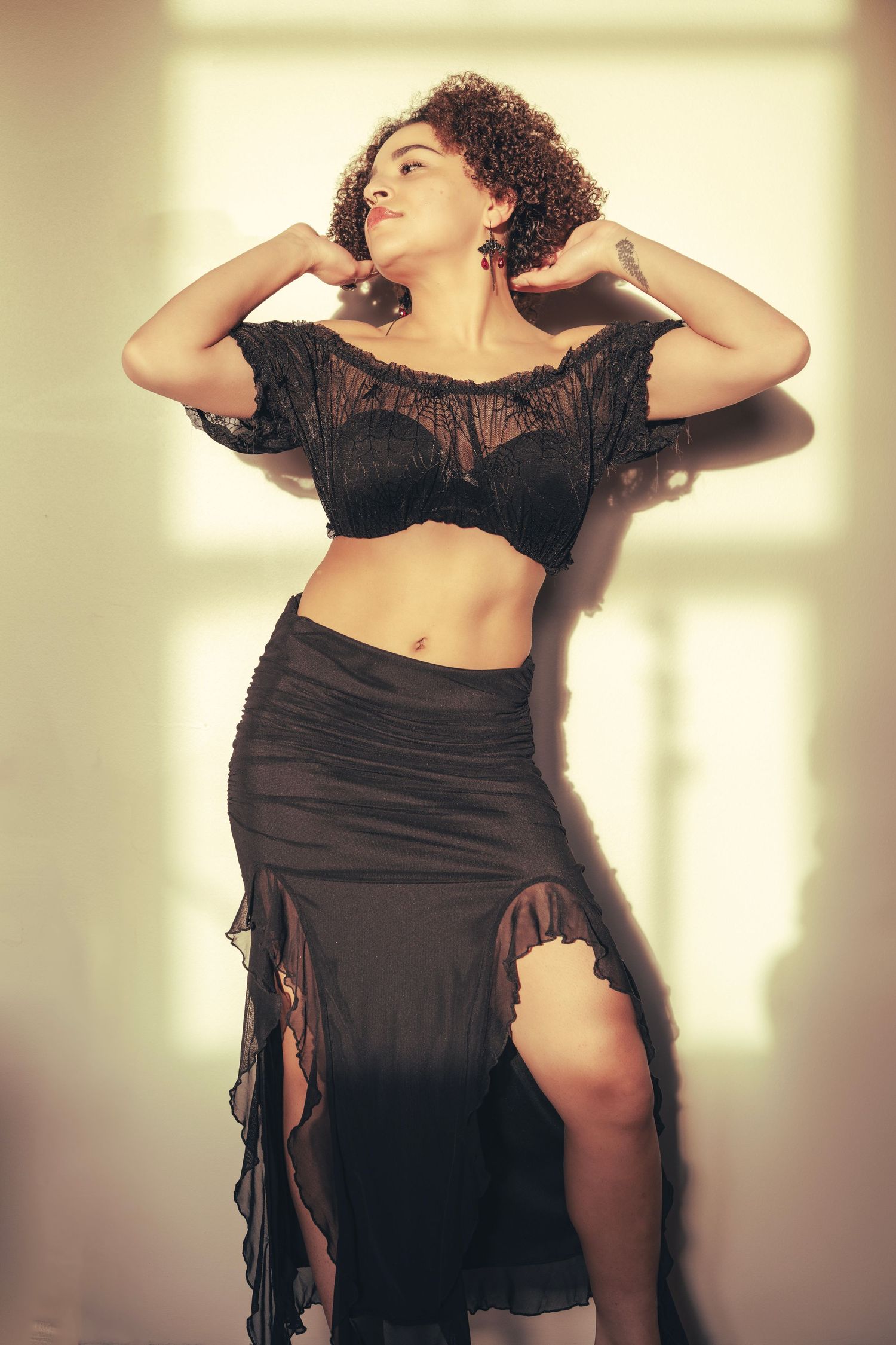 A fashion portrait featuring a black crop top and ruched skirt ensemble with sheer fabric details.