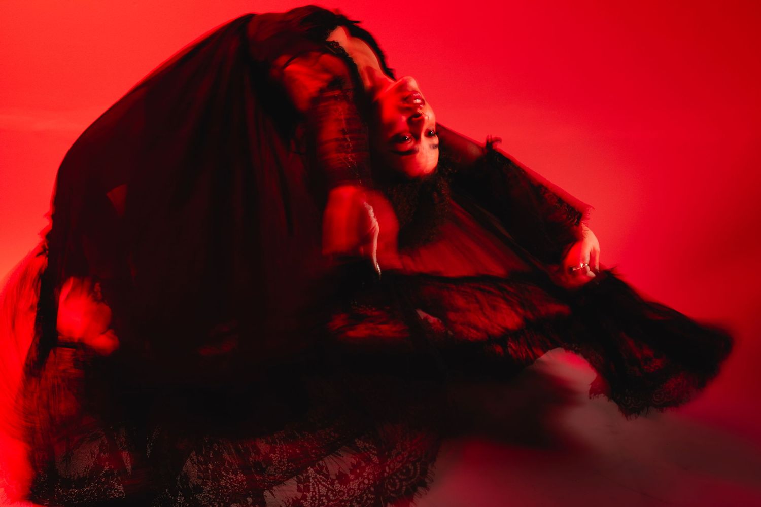 Dramatic silhouette of a dancer in red lighting performing expressive movements against a dark background.