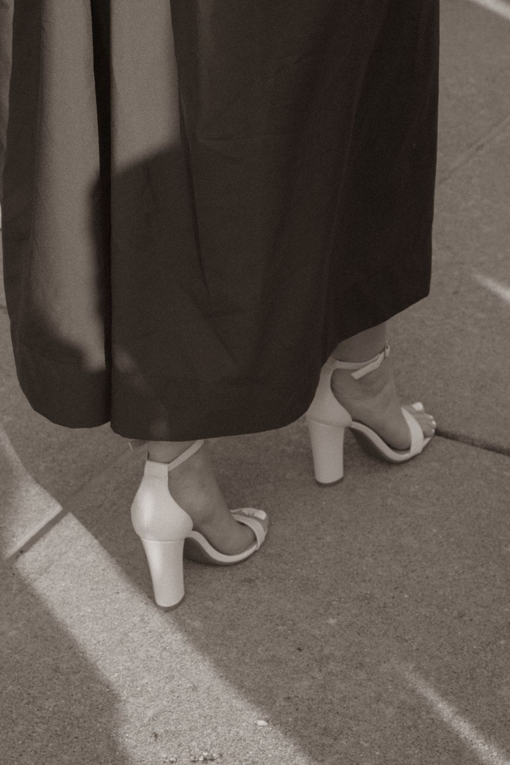 Close-up view of white heels worn under graduation gowns.