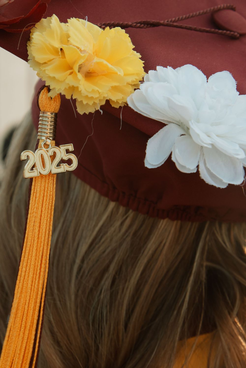 Graduation cap decorated with yellow and white paper flowers and gold tassel.