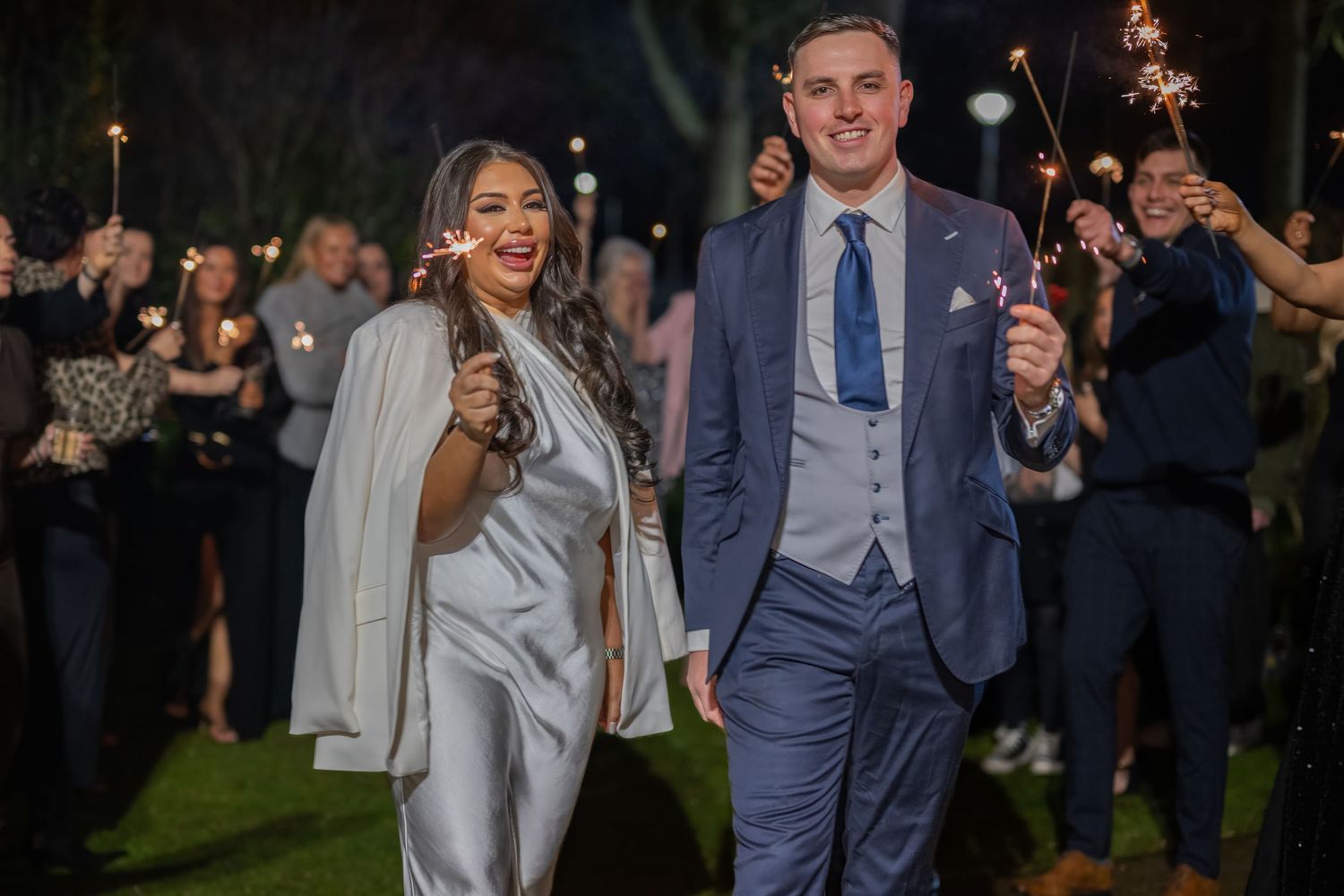 Wedding couple dances and celebrates with guests during evening reception in outdoor venue.