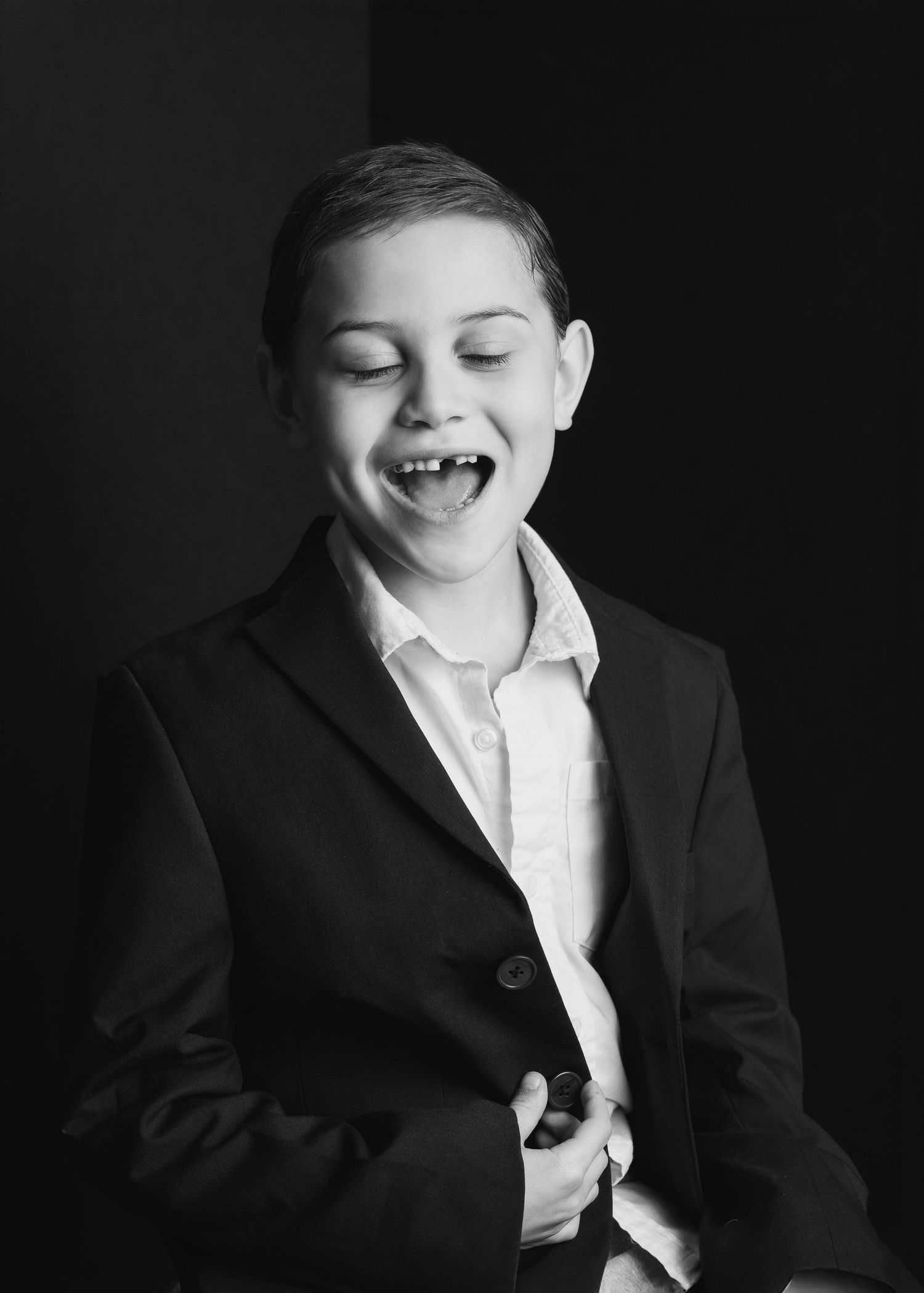 A studio black and white  portrait of a young boy missing one front too while smiling