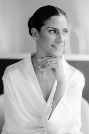 An elegant black and white portrait showing a woman in a white robe with a gentle smile.