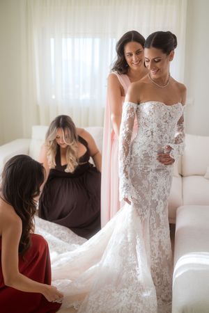 Wedding dress fitting session shows intricate lace details and flowing train in natural light setting.