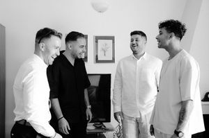 Group of groomsmen in white shirts and black pants getting ready.