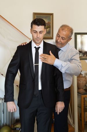 Two people in formal attire share a tender moment while getting ready for a special occasion.