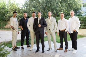 Wedding party members in mixed formal attire pose together outdoors.