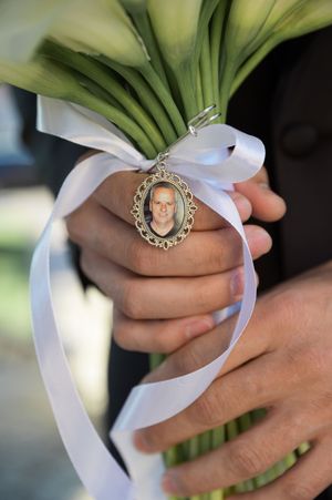 Wedding bouquet wrapped in white ribbon with a memorial charm attached.