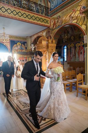 A wedding ceremony in a beautifully decorated Orthodox church with ornate painted walls and ceilings.
