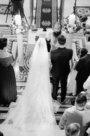 A black and white ceremony photo showing the back of a wedding dress in a church setting.