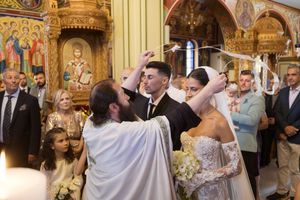 Wedding ceremony in progress inside an ornate golden church with decorative murals.