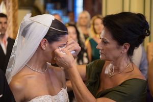 Emotional moment captured during wedding preparation with bride in white lace gown.