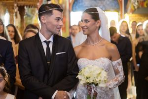 Elegant wedding ceremony in ornate church interior with decorative floral arrangements.
