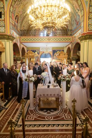 Traditional Orthodox wedding ceremony with guests gathered in beautifully decorated church interior.