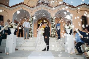 Newlyweds exit church steps under shower of confetti and sparklers at dusk.