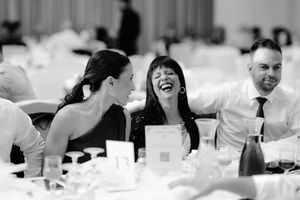 Black and white photo showing people dining and socializing at a formal event in an elegant banquet setting.