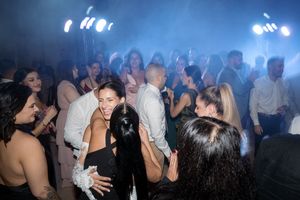 People dancing and socializing at a nightclub with bright blue lighting and a crowded dance floor.