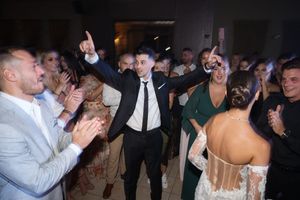 Wedding guests dancing and celebrating on a crowded dance floor during an evening reception.