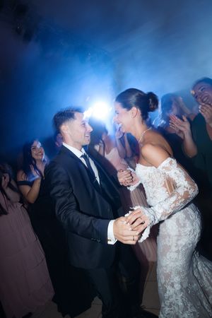 Couple shares a romantic dance under blue lighting at their wedding reception.