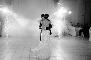 A couple dances elegantly in formal attire on a white dance floor illuminated by sparklers creating a magical atmosphere.