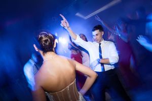 People dancing in a nightclub with blue lighting and raised hands create an energetic party atmosphere.