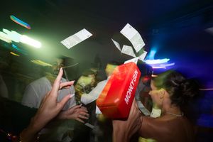 People dancing and celebrating at a nightclub with colorful lighting effects.