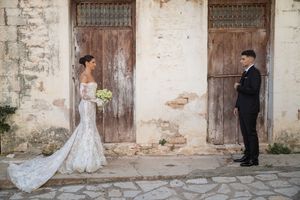 Romantic wedding photoshoot in front of rustic stone building with wooden doors and long flowing veil.