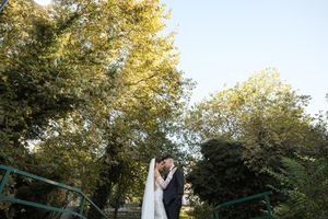 Wedding couple poses beneath golden autumn trees during sunset in a romantic outdoor setting.
