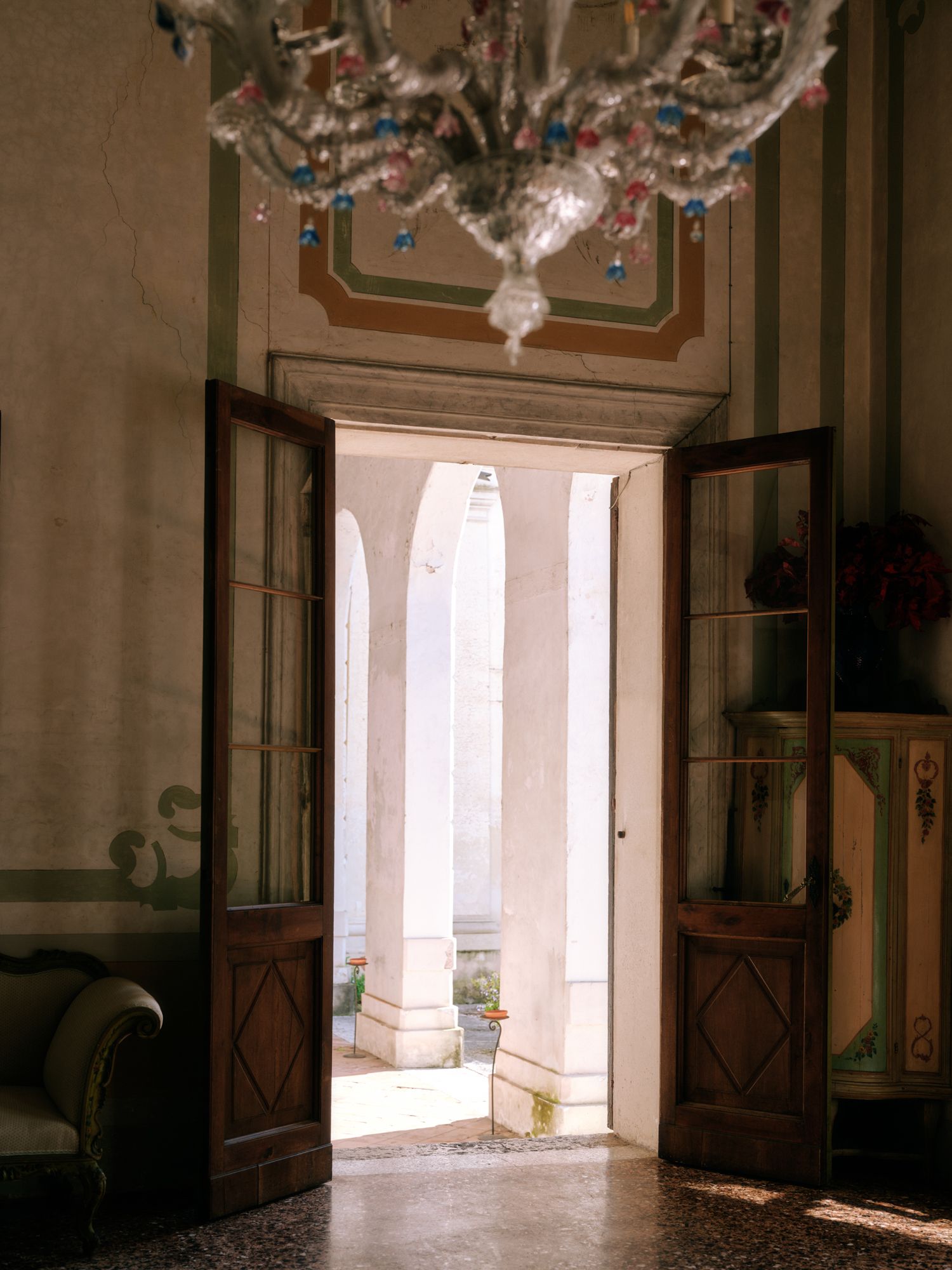 Ornate wooden double doors open to reveal white marble columns in a historic European building interior.