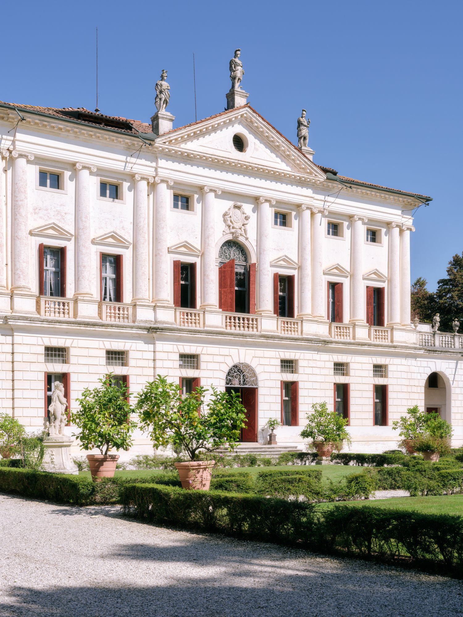 Elegant white Palladian villa with classical architectural details and manicured gardens in the foreground.