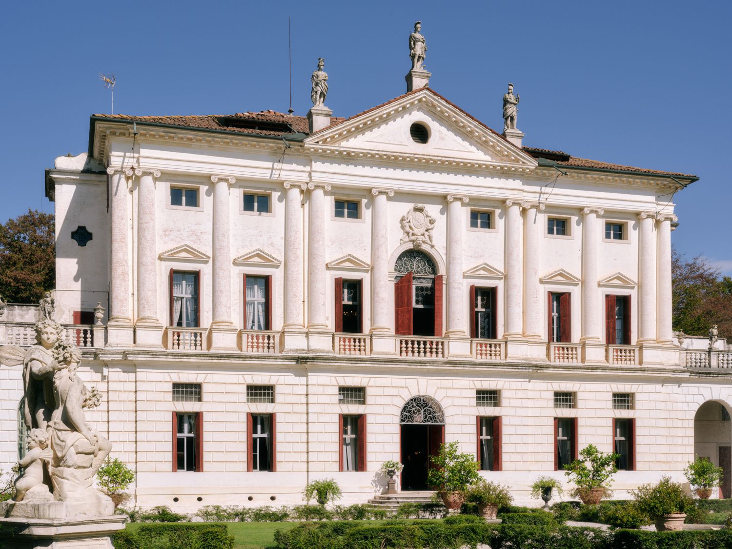 Ornate white neoclassical palace building with columns and decorative elements against a bright blue sky.